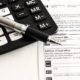 Pen, calculator, and CRA form for understanding tax litigation in Toronto explained by KR Law Firm - A Canadian Tax Law Firm in Toronto